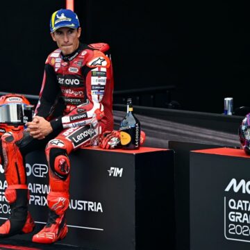 image רוכב MotoGP בחליפת מרוץ אדומה יושב על מדרגת הפודיום בגראז' אחרי מרוץ
